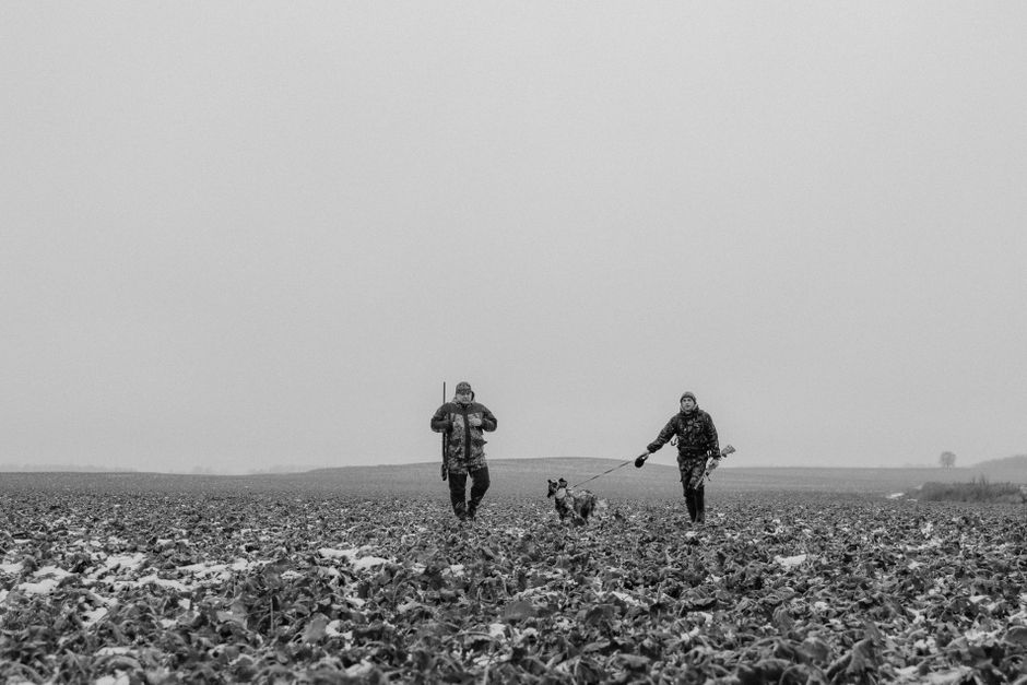 Chasseurs et chien traversant un champ d'hiver en Ombrie