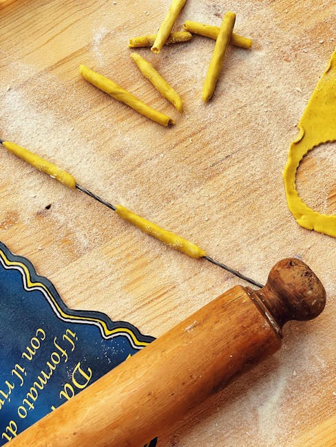 Deegrol en fijne gele strookjes pasta op bebloemd houten bord