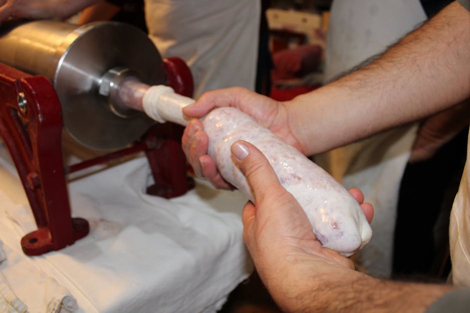 Hands stuffing sausage casing on grinder, traditional Calabria 'nduja preparation