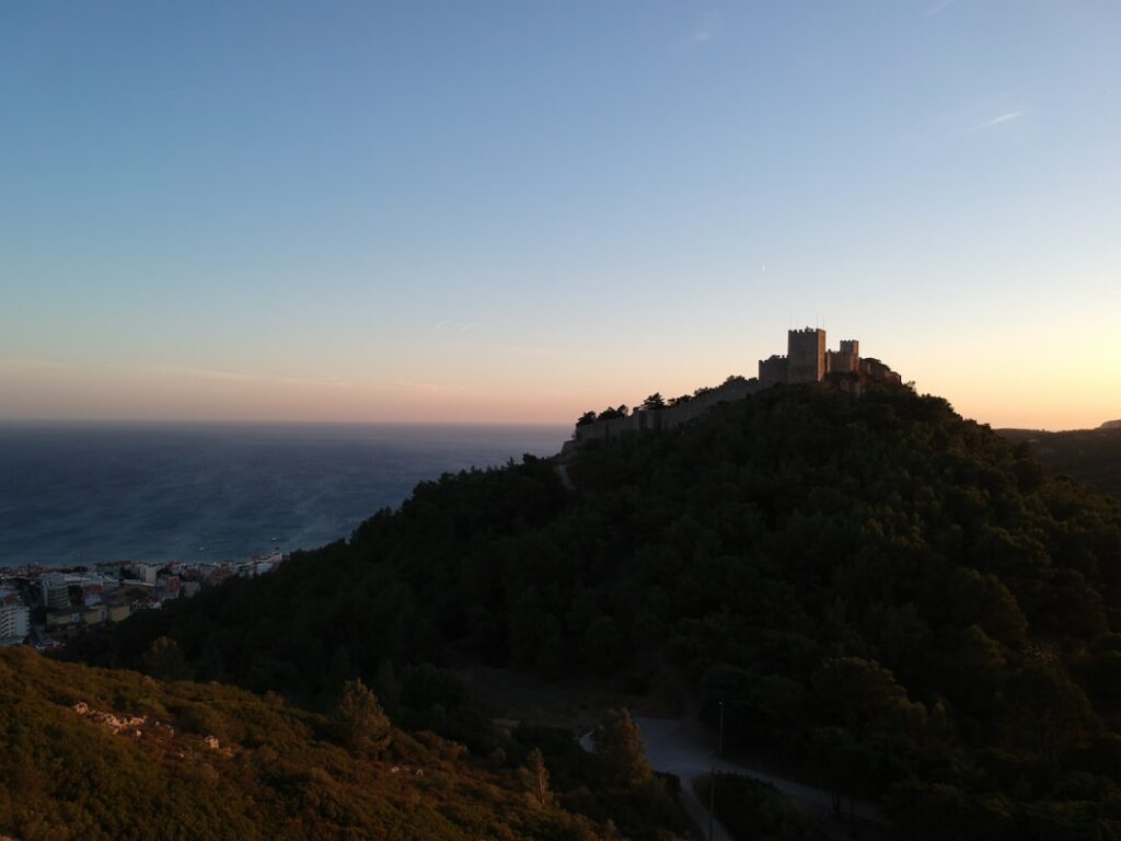 Château médiéval silhouetté au sommet d'une colline face à la mer en Calabre