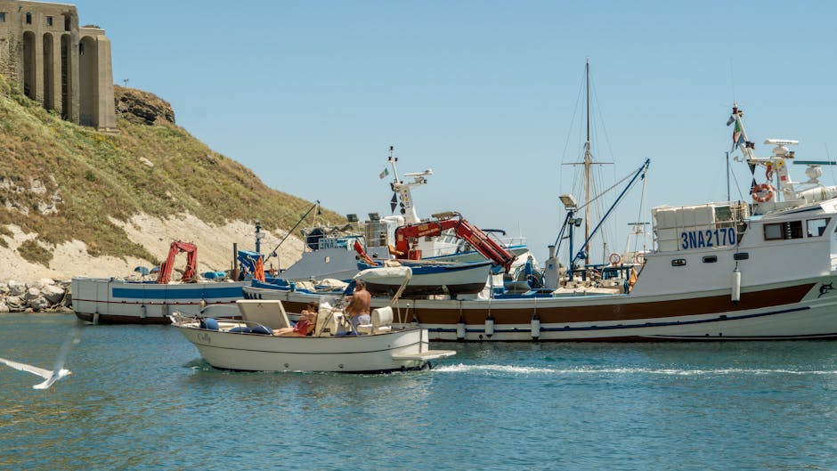 Kleine Fischerboote im Hafen vor felsiger Küste in Kalabrien.