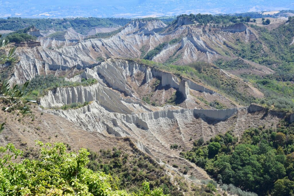 Erosionslandschaft mit markanten Lehmfurchen und vereinzelten Olivenbäumen in Kalabrien