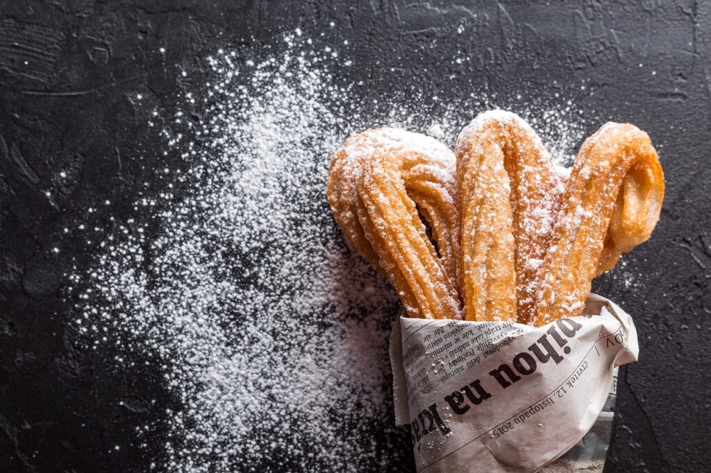Churros mit Puderzucker in Zeitungspapier, serviert in Kalabrien