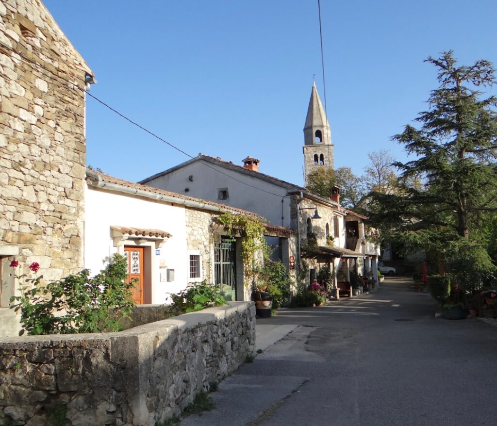 Uriges Dorf mit steinernen Häusern, Blumenkübeln und Kirchturm in Kalabrien