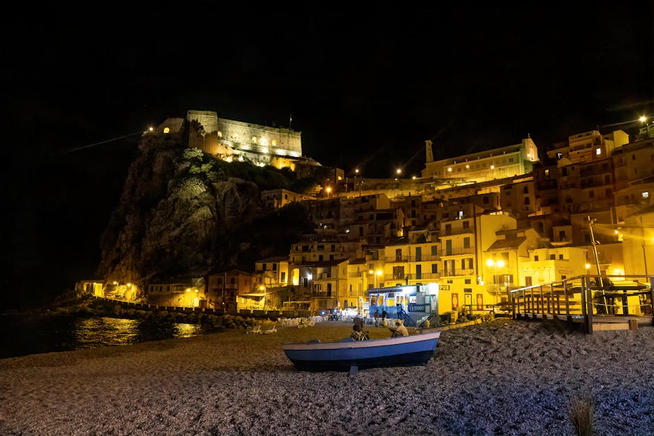 Verlicht kustdorp bij nacht met boot op kiezelstrand in Calabrië