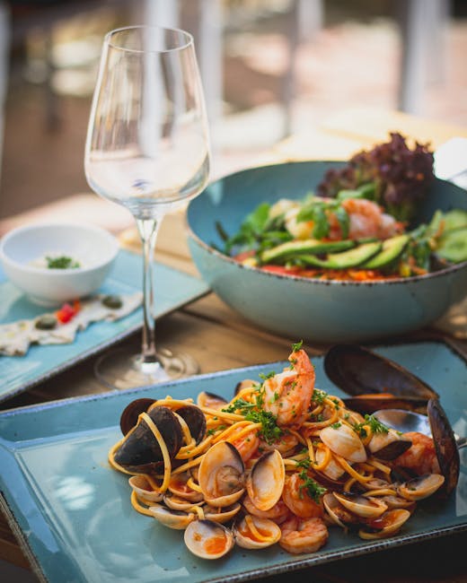 Meeresfrüchte-Pasta, Salat und leeres Weinglas auf einem Tisch in Kalabrien