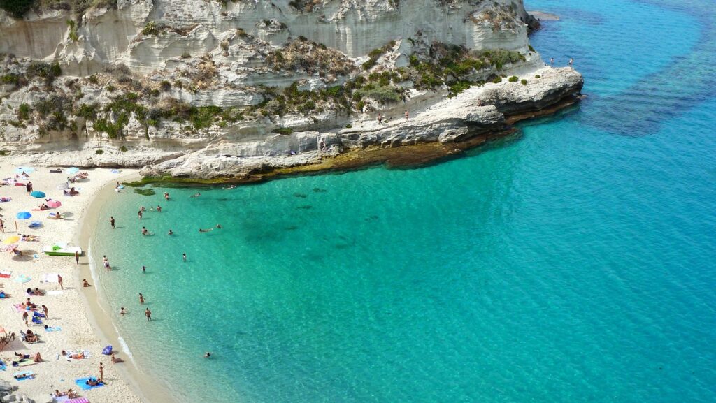 Spiaggia rocciosa della costa calabrese con acqua turchese e bagnanti