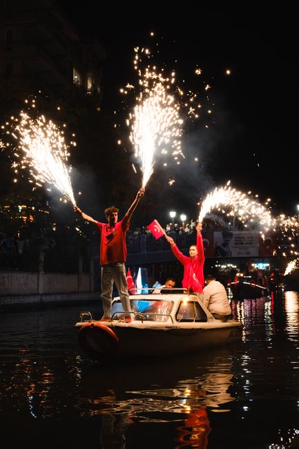 Mensen op boot in Calabrië met fonkelende vuurwerkstokken tijdens nachtelijke optocht