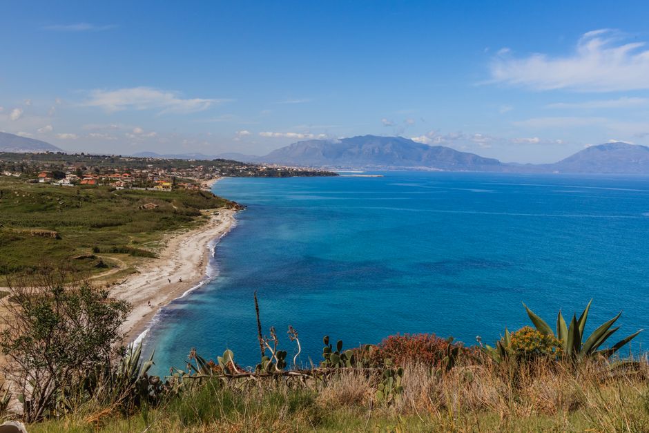 Plage de sable bordée d'îlots d'agave, vue sur la baie calabraise