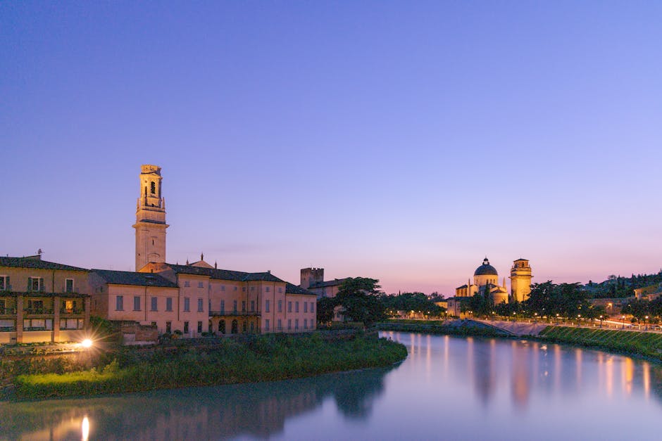 Rive de l'Adige à Trente au crépuscule, clocher et coupole illuminés
