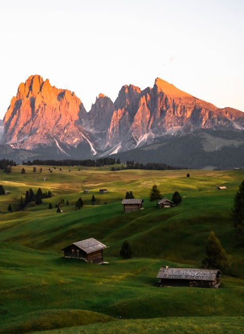 Alpenglow sur les sommets des Dolomites et chalets verdoyants