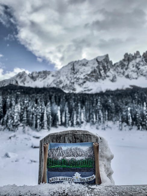 Plaque indiquant Lago Carezza devant lac gelé et Dolomites
