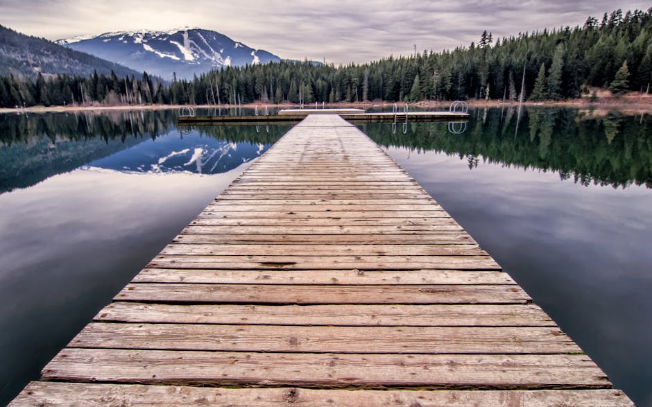 Ponton en bois s'avançant sur un lac alpin près de Trente, montagnes réfléchies