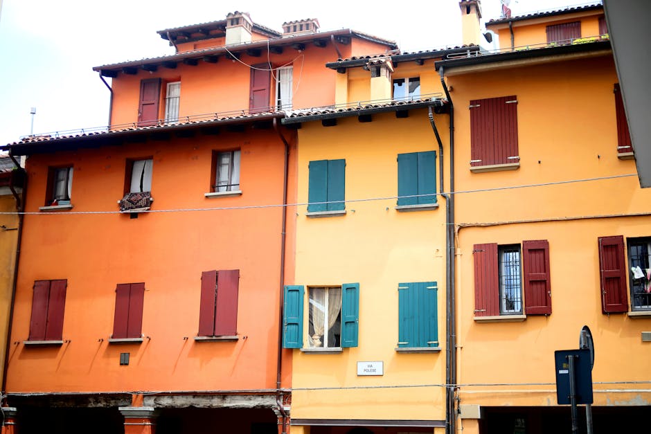 Façades colorées orange et jaunes à volets, rue étroite de Trente