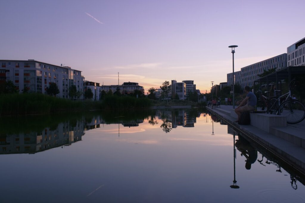 Miroir d'eau réfléchissant immeubles et passants au crépuscule à Trente