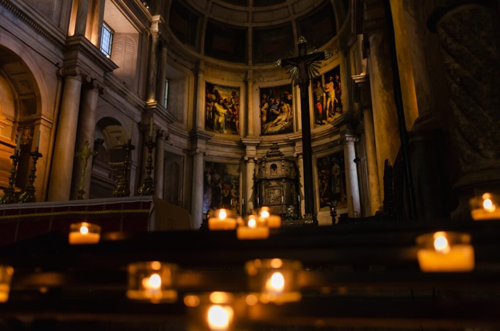 Kerzen im Vordergrund vor dem kunstvollen Altar einer Kirche in Trient.