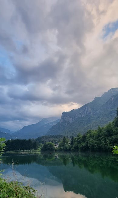 Lac calme reflétant montagnes et ciel orageux près de Trente