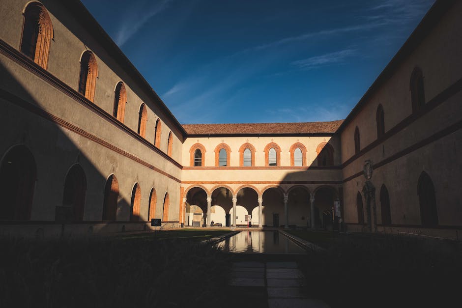 Sonniger Innenhof mit Arkaden und Wasserbecken im historischen Trient.