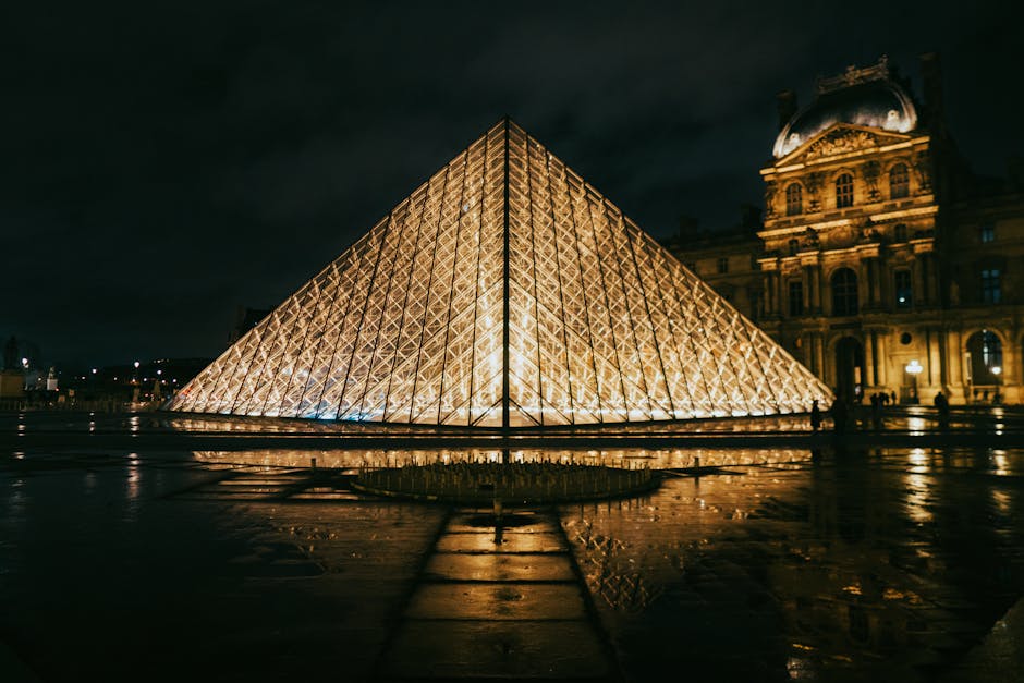 Pyramide du Louvre illuminée la nuit, reflet sur le sol mouillé à Paris