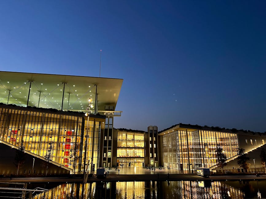 Bâtiment moderne illuminé au bord de l'eau à Trente au crépuscule