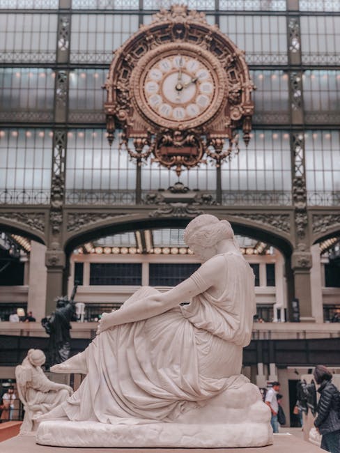 Statue sculptée au premier plan, grande horloge du musée d'Orsay derrière à Paris