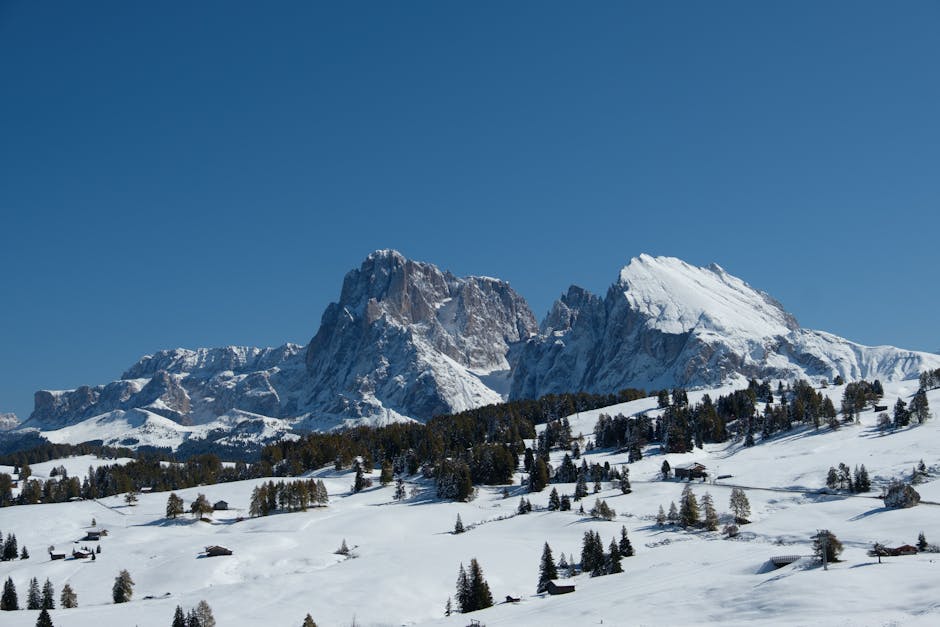 Plateau enneigé des Dolomites avec chalets dispersés sous un ciel bleu
