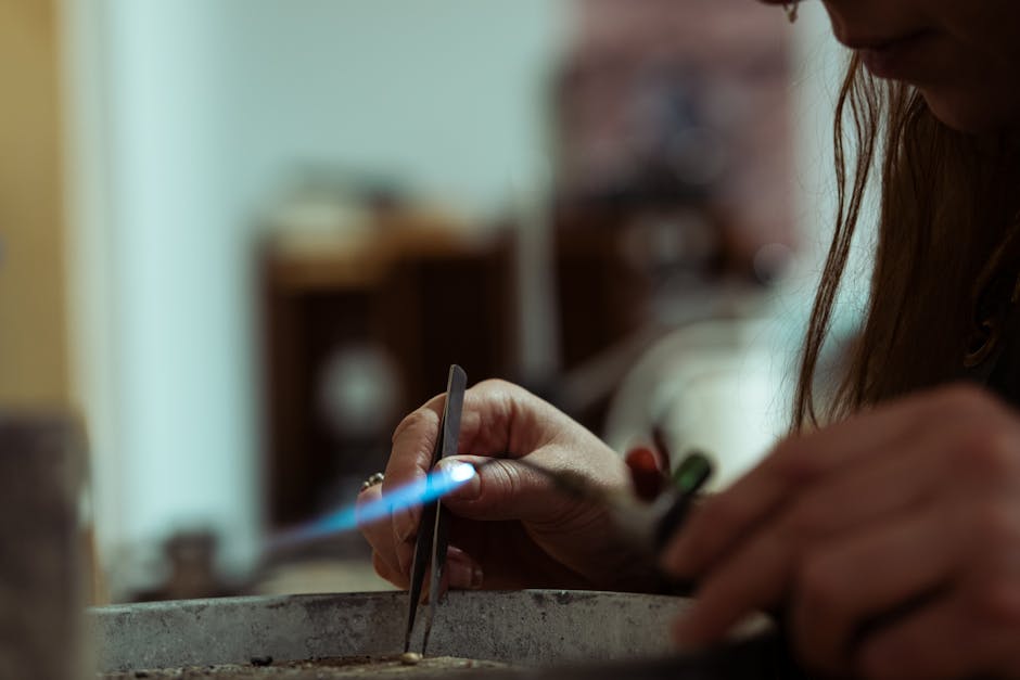 Artisan(e) du métal chauffant une pièce au chalumeau dans un atelier à Trente