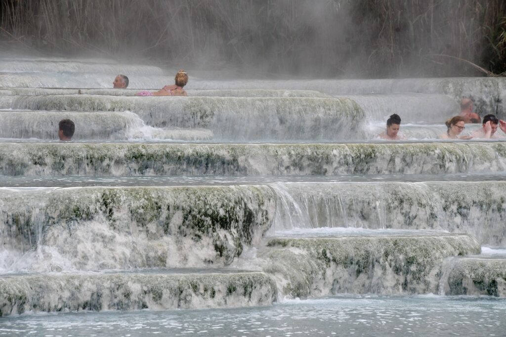 Terrasses calcaires remplies d'eau thermale et baigneurs enveloppés de vapeur