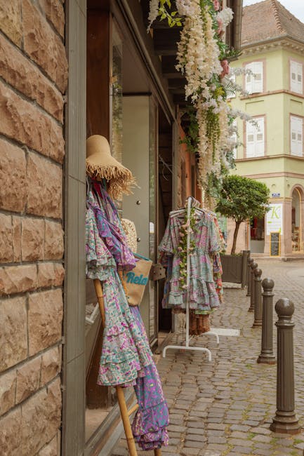 Robes fleuries et chapeau de paille exposés devant une boutique à Trente