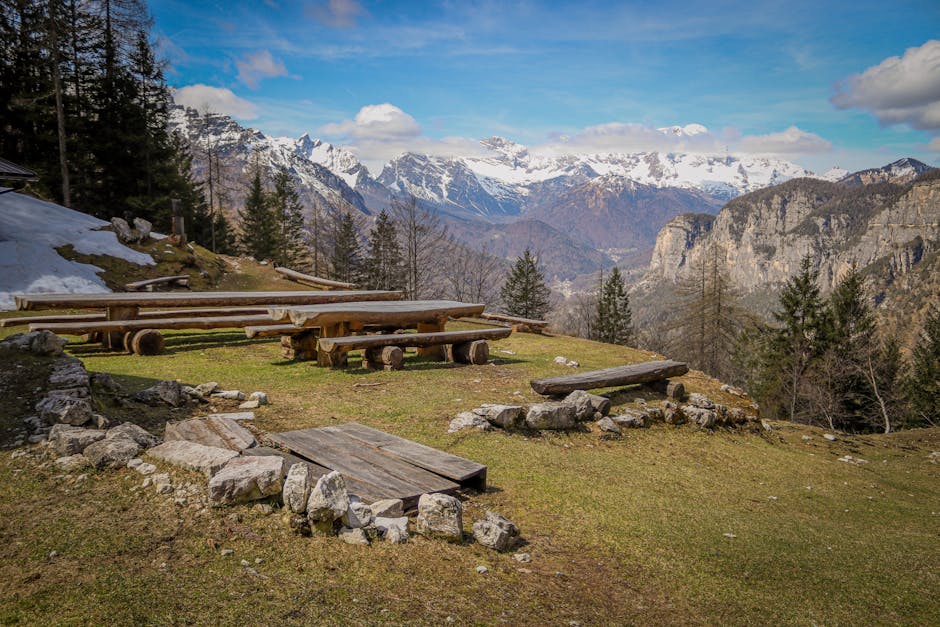 Aires de pique-nique en bois sur terrasse alpine près de Trente, montagnes enneigées.