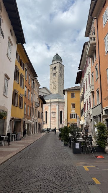 Ruelle pavée menant à la cathédrale de Trente, façades colorées.