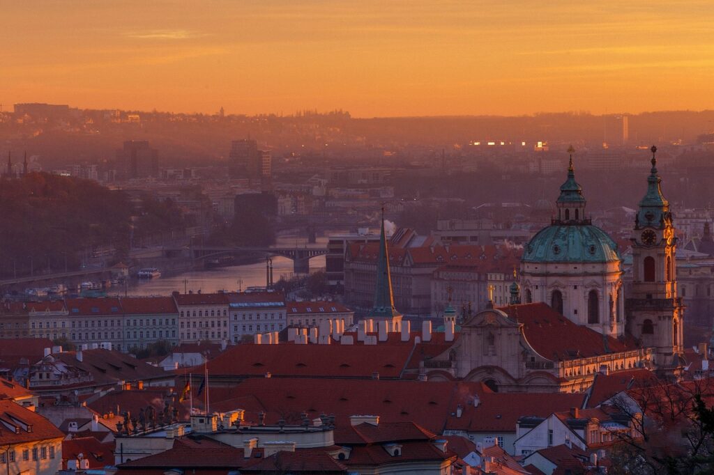Cupole e tetti di Praga illuminati dall'alba arancione