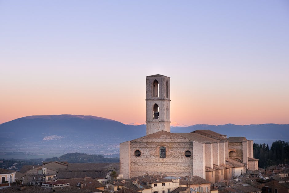 Chiesa medievale su colle con campanile e montagne sullo sfondo