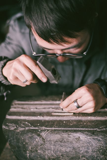 Juwelier in atelier in Trente buigt klein metalen stuk met hamer