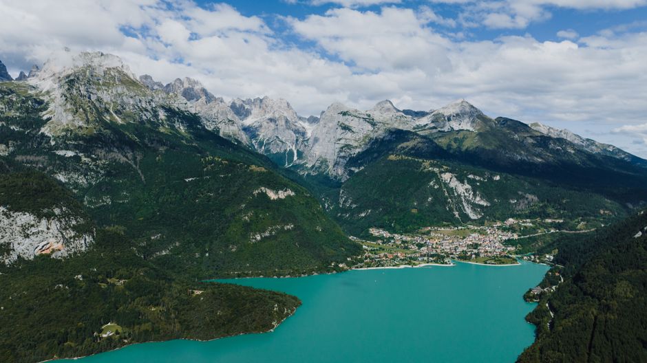 Lac turquoise bordé d'un village et montagnes escarpées près de Trente