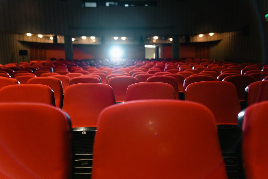 Red theater seats in Trento auditorium with projector light beaming forward