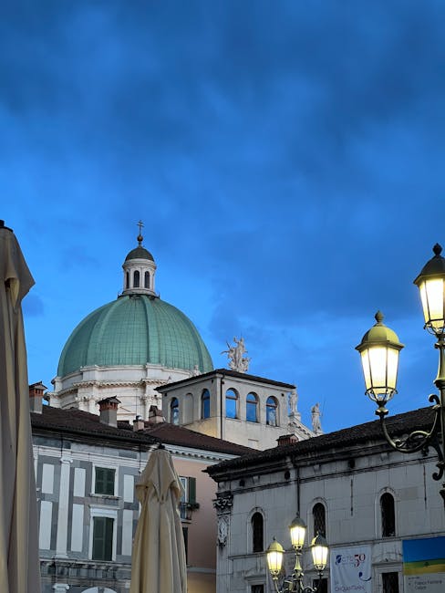 Green domed church rising above Trento square under deep blue evening sky
