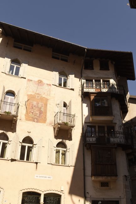 Façade ancienne à Trente avec fresque effacée et balcons en fer