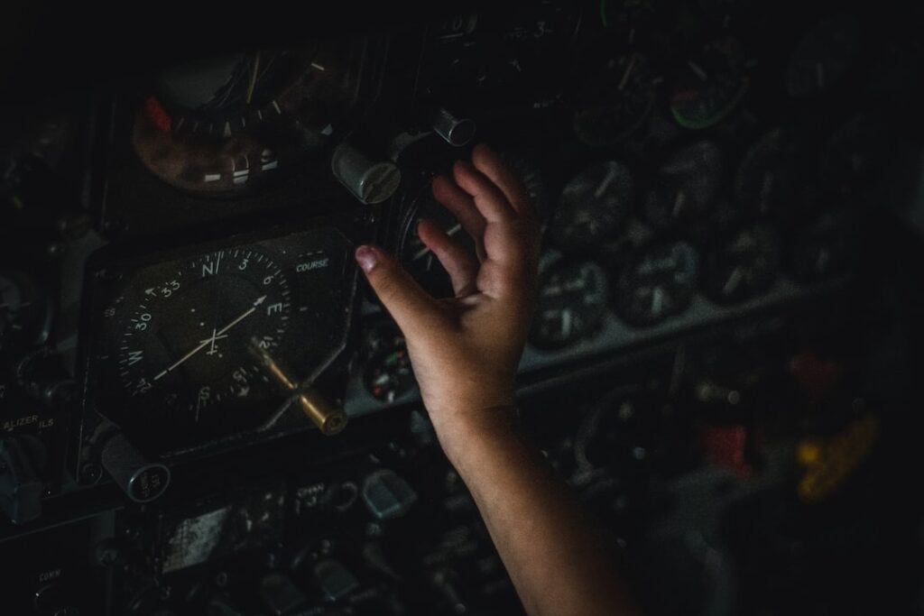 Main d'enfant touchant les instruments d'un cockpit sombre et ancien