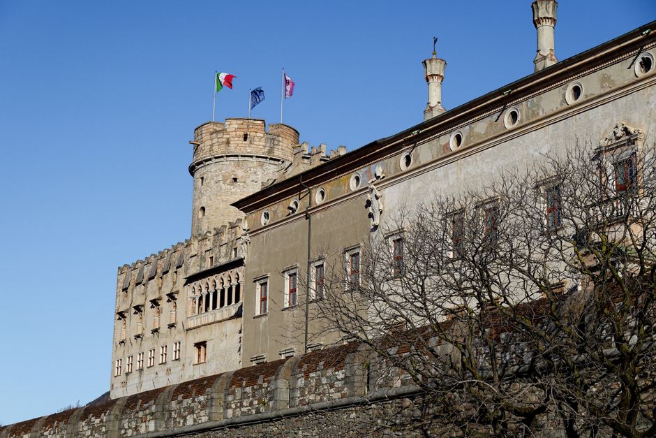 Steenachtige toren met vlaggen en gevel van kasteel in Trento