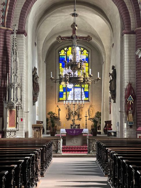 Lange kerkgang met houten banken en glas-in-loodraam in Trento