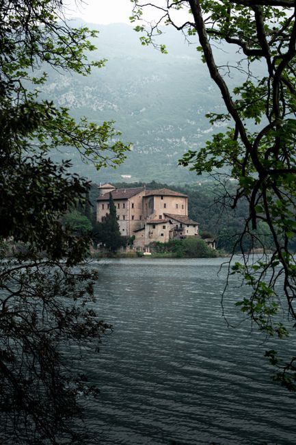 Kasteel aan het meer gezien tussen bomen bij Trento