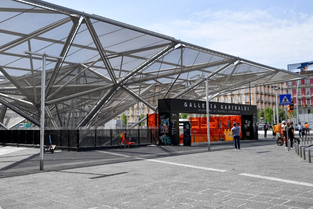 Grote metalen overkapping bij een treinstation met oranje ingang