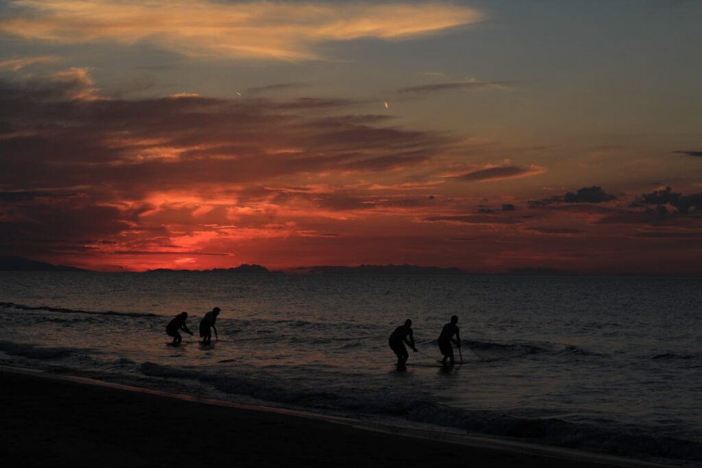 Silhouetted people wading in the Adriatic near Bari at sunset