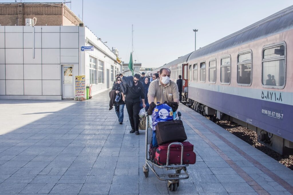 Reiziger duwt bagagekar langs trein op een perron
