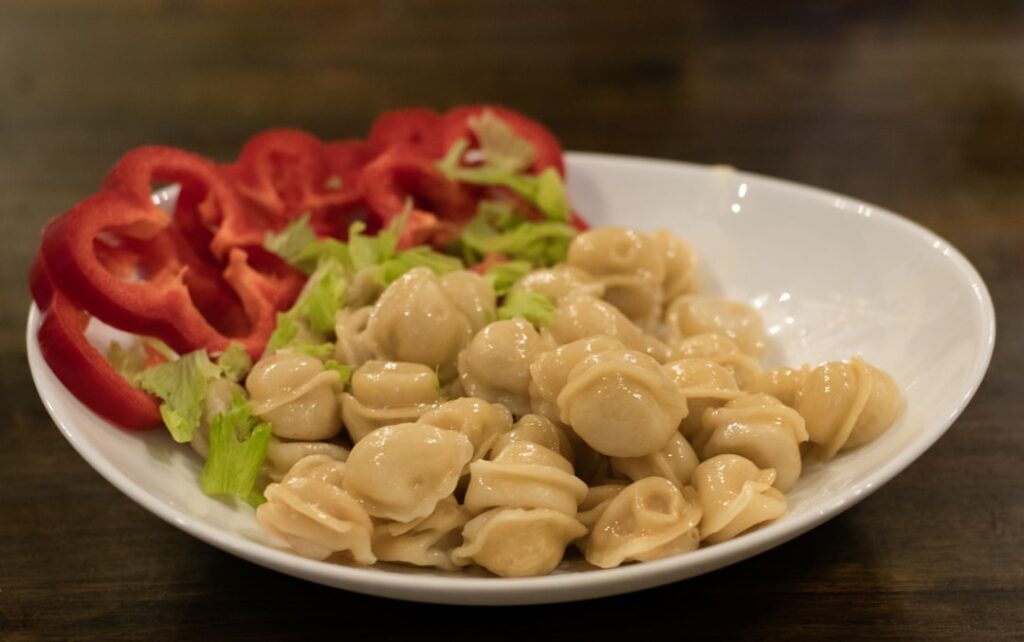 Piatto di orecchiette pugliesi servite con peperoni e insalata a Bari