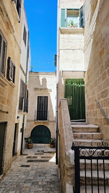 Quiet stone passageway in Bari with stairs and green shutters.