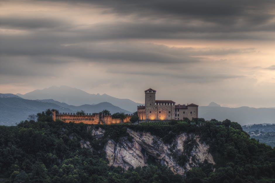 Stone fortress perched on a rugged cliff beneath cloudy skies.