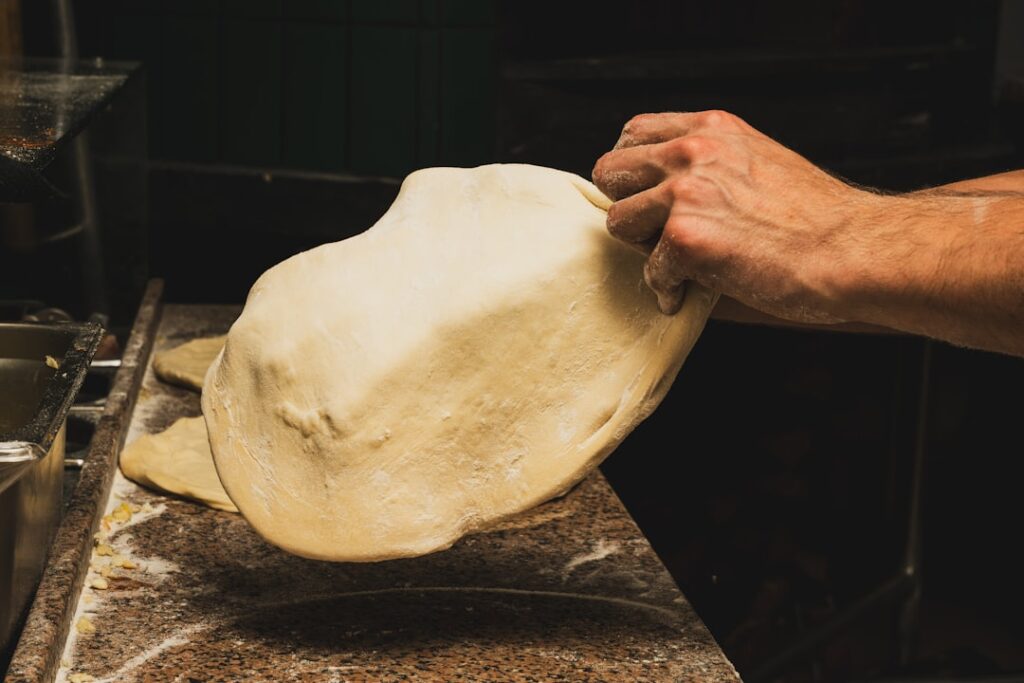 Hands stretching dough on floured counter in a Bari bakery.