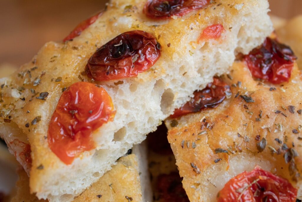 Close-up of Bari focaccia topped with roasted cherry tomatoes and herbs.